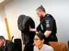 Thomas Møller Olsen covering his face from photographers at the Reykjanes district court today.